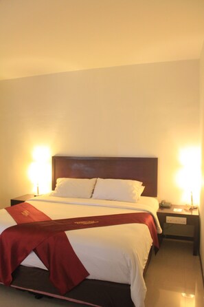 A hotel room with a neatly made bed, a wooden headboard, and two bedside lamps. - Hotel GRAN CENTRAL (Manado)
