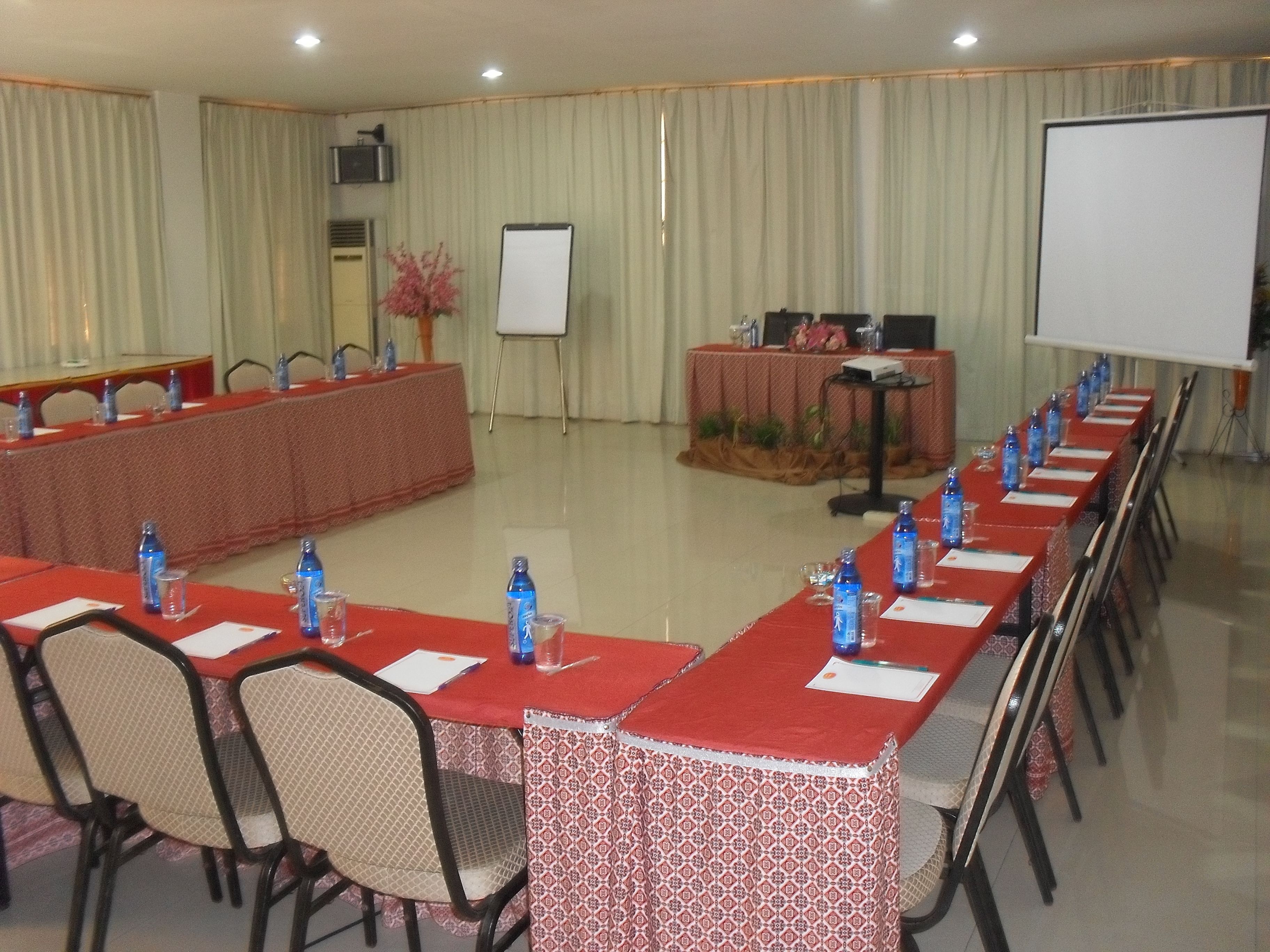 A conference room with a long table, chairs, water bottles, and a whiteboard.