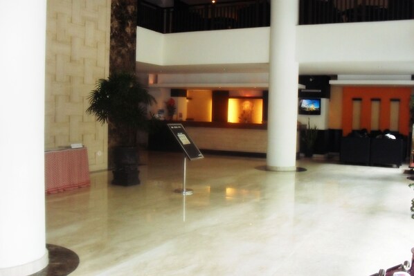 A lobby with a reception desk, a large potted plant, and a signboard. - Hotel GRAN CENTRAL (Manado)