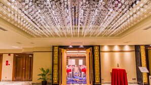 A hotel lobby with a marble floor, a red table with a sign, and a potted plant. - Nu Hotel (Bintulu)