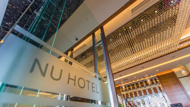 The NU Hotel's entrance with a modern glass facade, a visible indoor garden, and a ceiling with a patterned light fixture. - Nu Hotel (Bintulu)