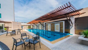An outdoor swimming pool area with a pergola, seating, and a poolside bar. - Nu Hotel (Bintulu)