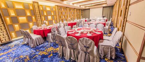 A banquet hall with round tables, chairs, and a blue carpet with yellow patterns.