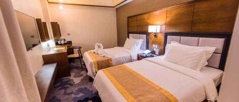 A hotel room with two beds, a desk, a chair, and a mirror.