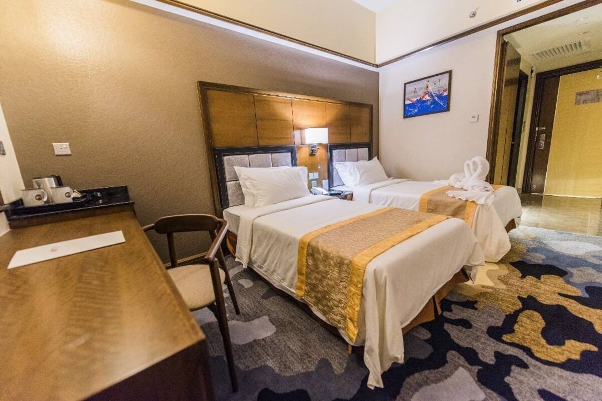 A hotel room with two beds, a desk, and a chair.