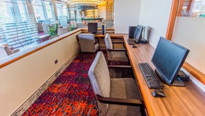 A modern office space with multiple workstations, a patterned carpet, and large windows providing natural light. - Nu Hotel (Bintulu)