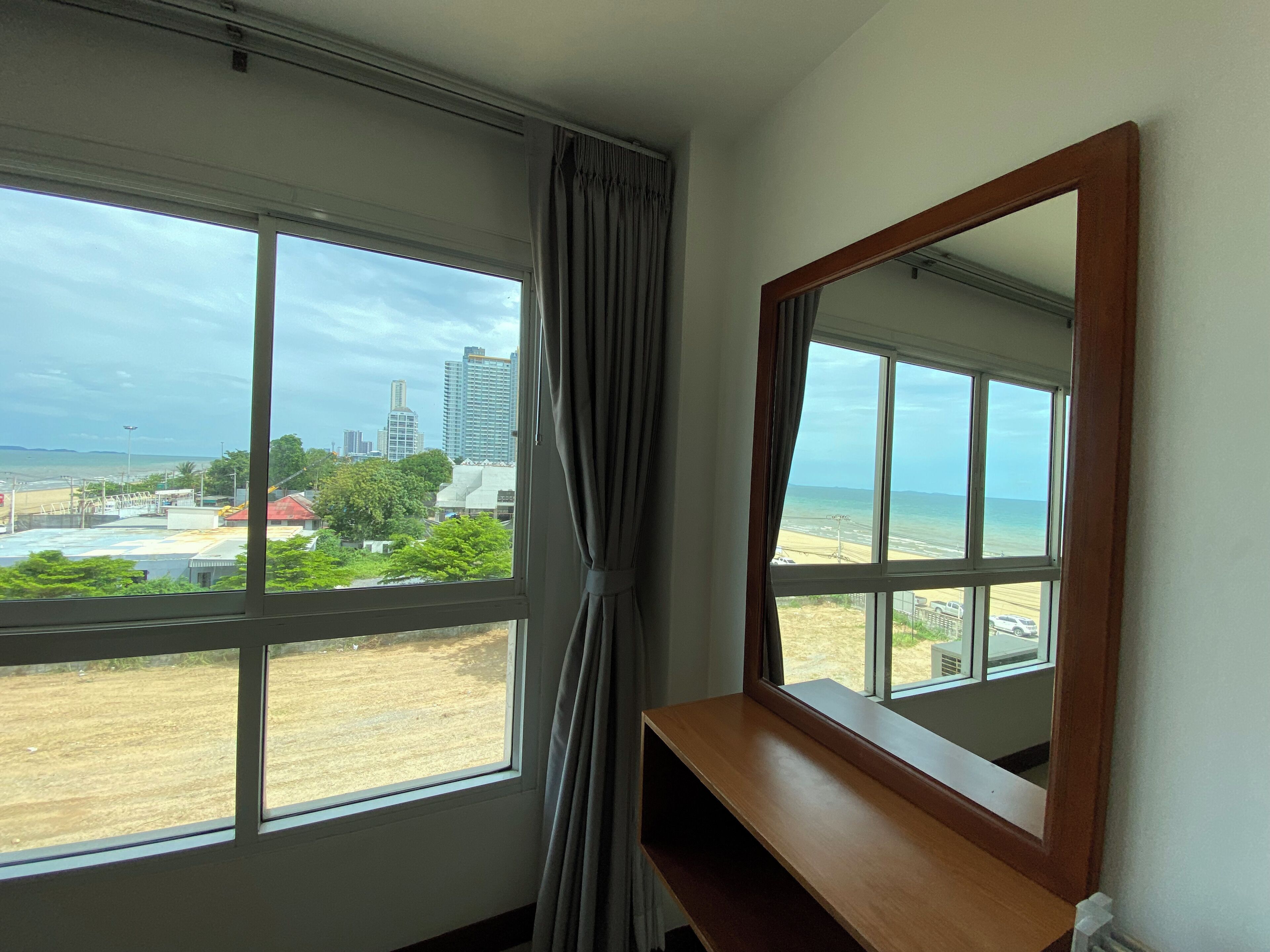 A room with a large window, a wooden desk, and a mirror.