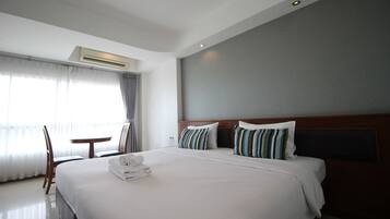 Una habitación de hotel con una cama grande, una mesita de noche, una silla y una ventana con cortinas.