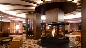 A modern lobby with a central fire feature, wooden paneling, and patterned flooring. - Dorukkaya Ski & Mountain Resort (Seben)