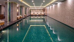 A modern indoor swimming pool with a clear water surface, surrounded by lounge chairs and a tiled wall with a geometric pattern. - Dorukkaya Ski & Mountain Resort (Seben)