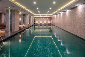 Una piscina techada, sillones reclinables de piscina