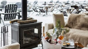 A cozy outdoor seating area with a wood-burning stove, lounge chairs, and a table with a festive centerpiece. - Dorukkaya Ski & Mountain Resort (Seben)