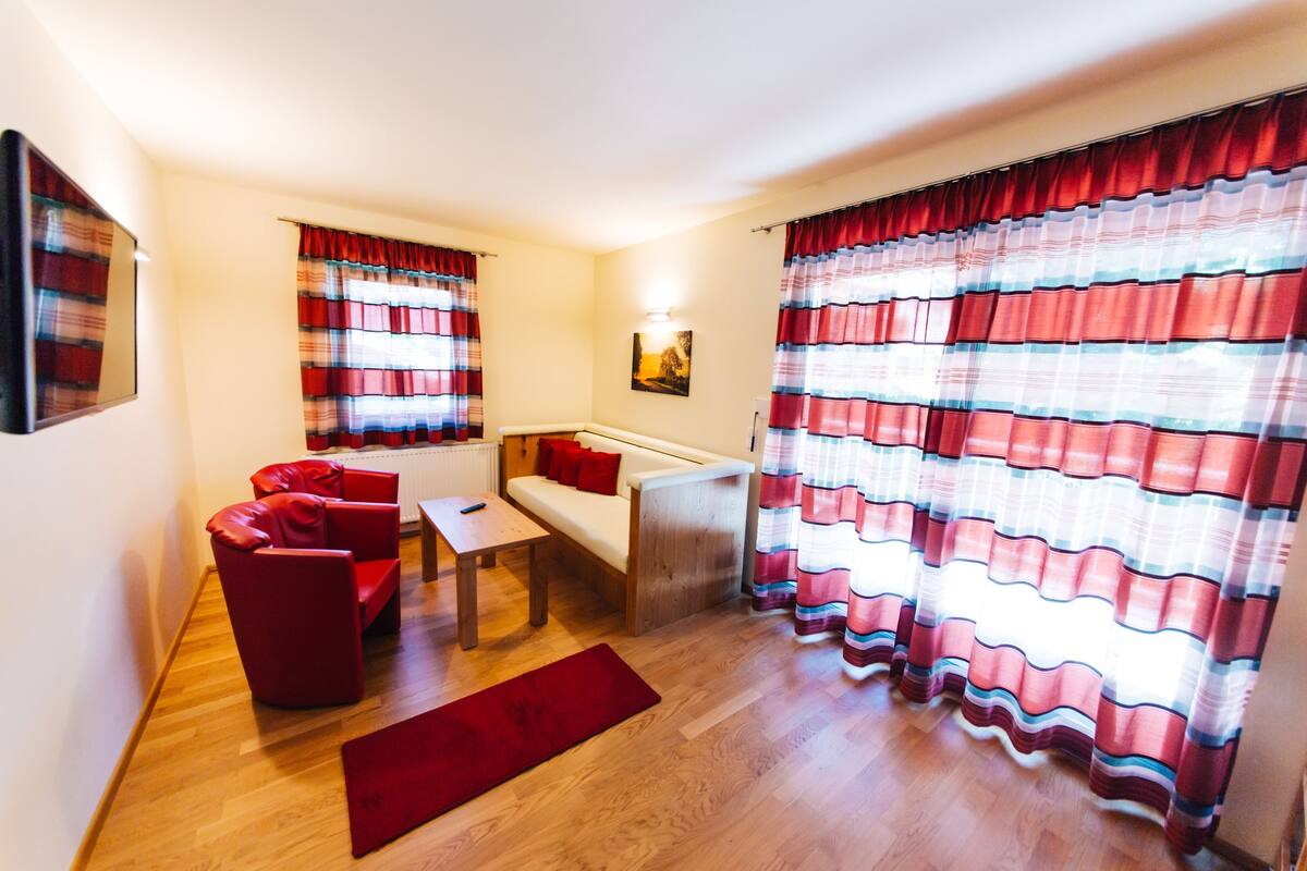 A living room with a sofa, a small table, and a red rug.