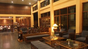 A spacious lobby with high ceilings, a seating area with cushioned sofas and chairs, a glass coffee table, and a decorative vase. - Mutiara Hotel Cilacap (Cilacap)