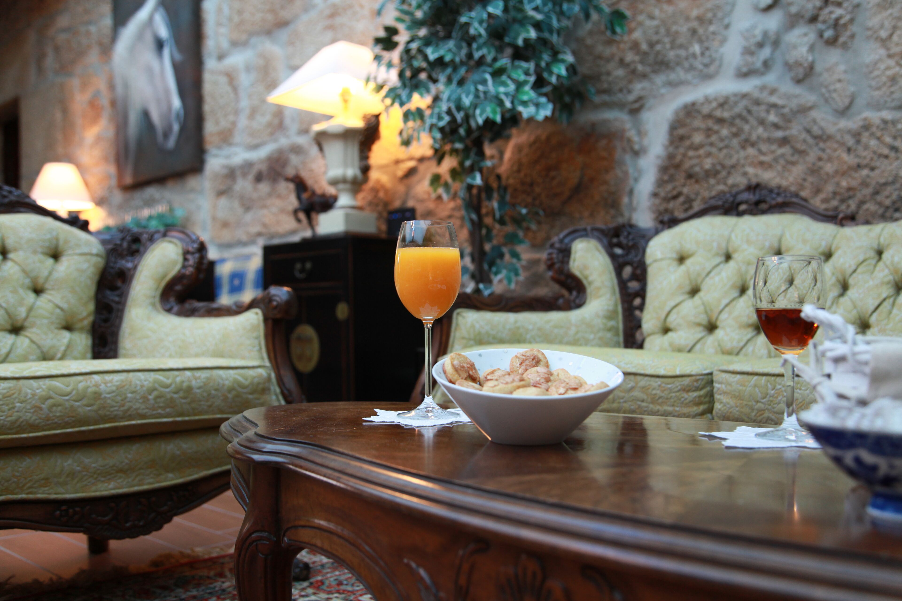 Une table à manger avec un bol de céréales, deux verres de jus d’orange et un verre de vin rouge.