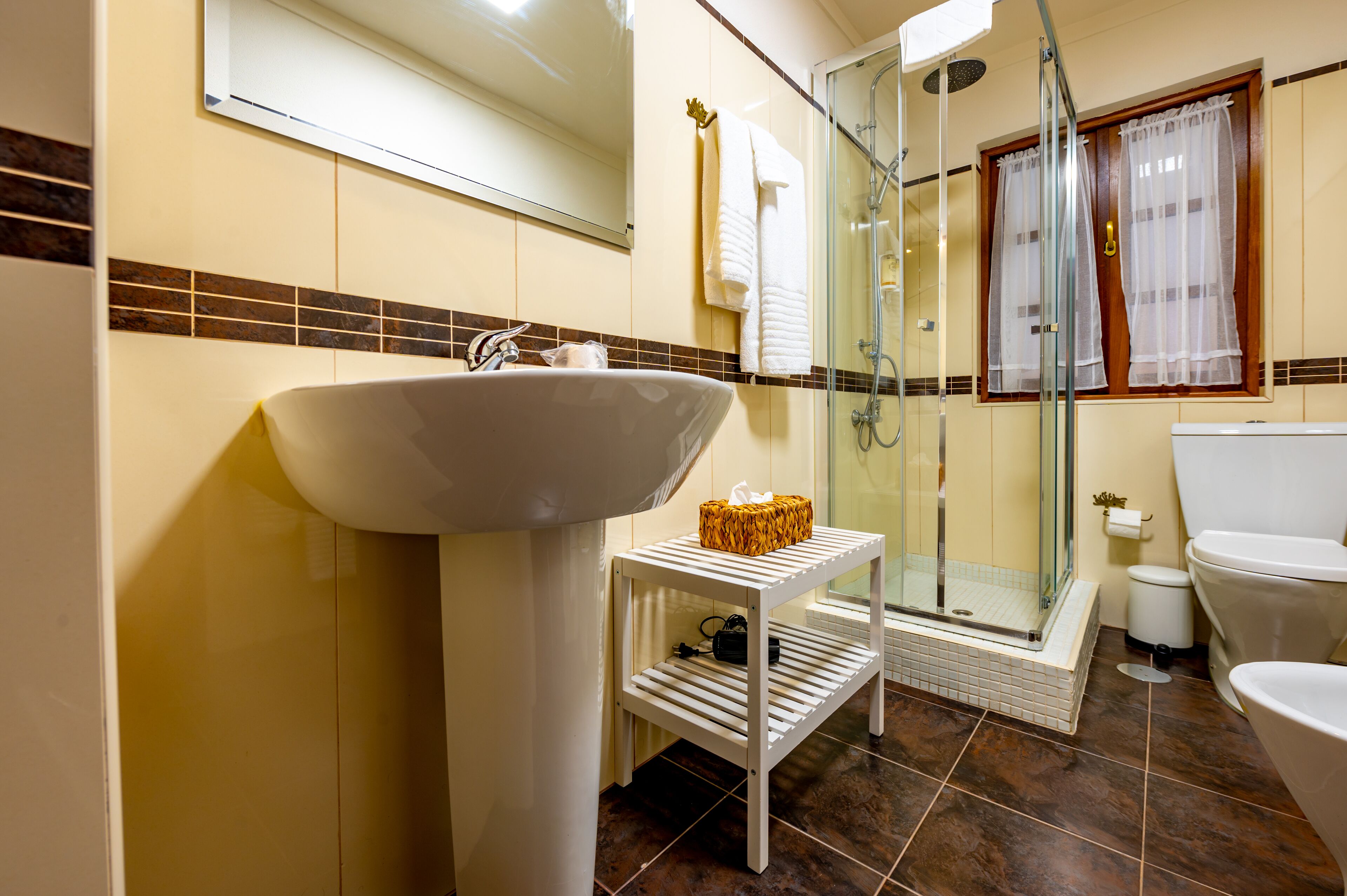A bathroom with a sink, mirror, shower, and toilet.