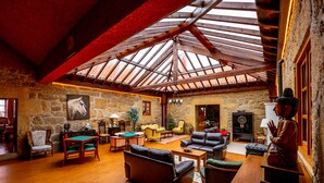 A spacious room with a high wooden ceiling, stone walls, and a billiards table.