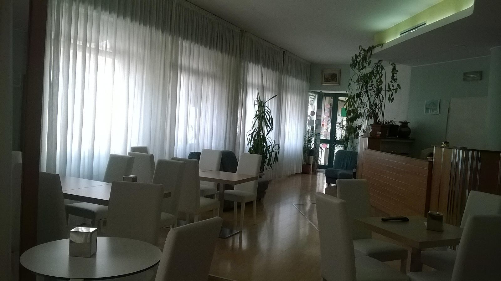 Eine Hotelhalle mit Sitzgelegenheit, einer Rezeption und Topfpflanzen.