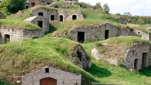 A series of stone buildings with grass-covered roofs, some with open doors, on a grassy hill. - Hotel La Pergola (Rionero in Vulture)