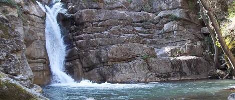 A waterfall cascading over rocky terrain with clear water flowing into a pool below.