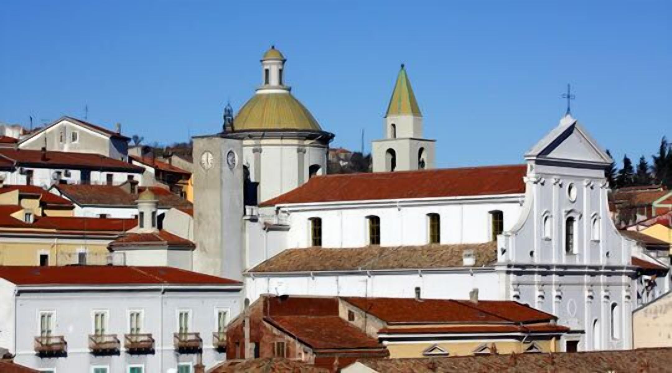 A historic town with white buildings, a church with a green dome, and a bell tower.