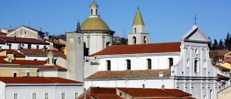 A historic town with white buildings, a church with a green dome, and a bell tower.