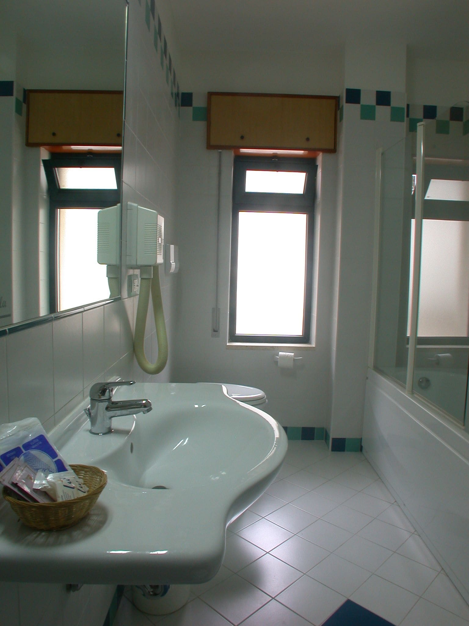 A bathroom with a sink, mirror, and window.