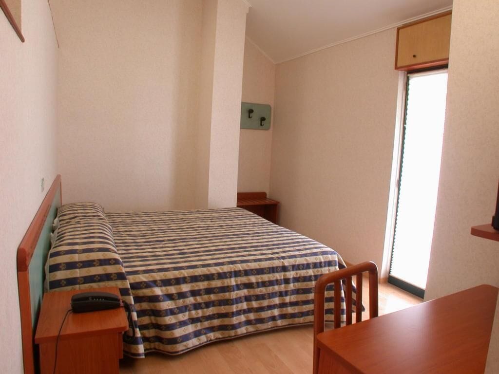 Un alojamiento pequeño y de una sola habitación, con cama, escritorio y silla.