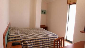 Un alojamiento pequeño y de una sola habitación, con cama, escritorio y silla.