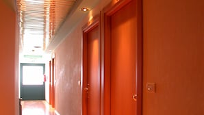 A hallway with wooden floors and doors, leading to a bright room. - Hotel La Pergola (Rionero in Vulture)