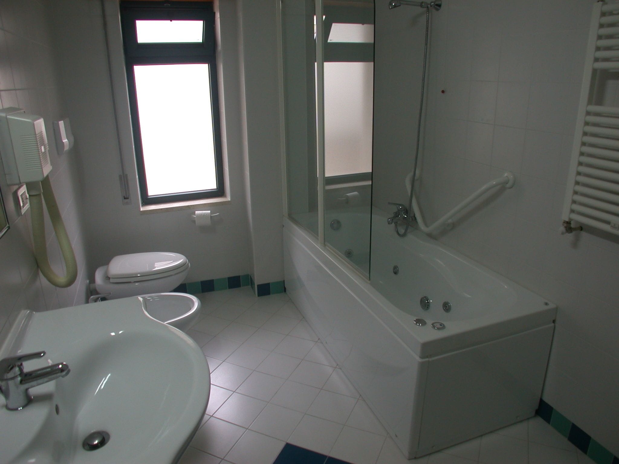 A bathroom with a toilet, sink, bathtub, and a window.