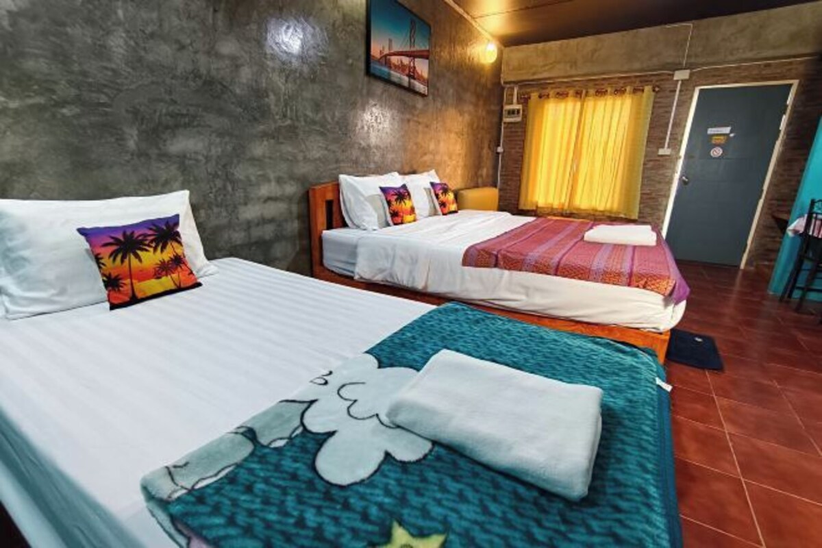 Two beds with pillows, a wall with a painting, a door, and a curtain.