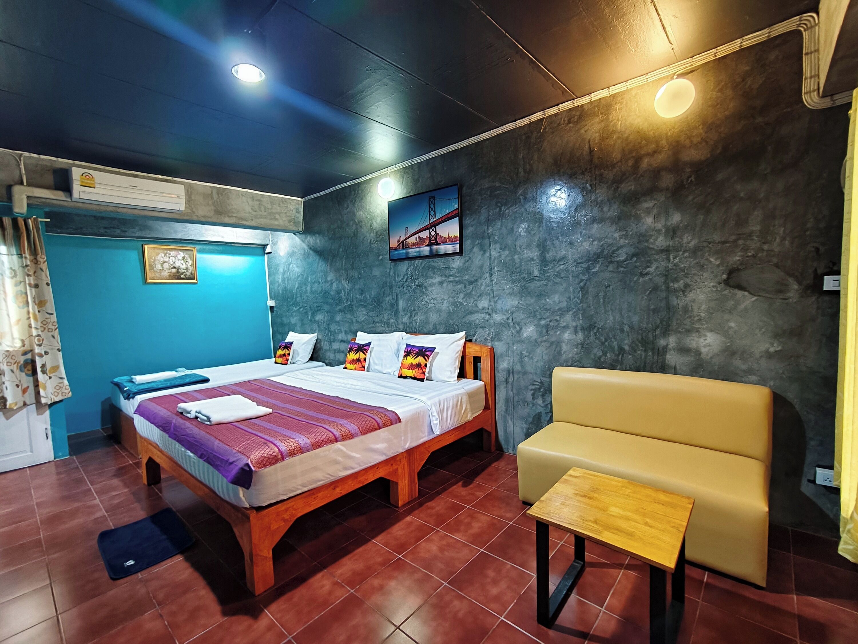 Hotelkamer met een bed, een slaapbank, een tafeltje, een schilderij aan de muur en een airconditioner.