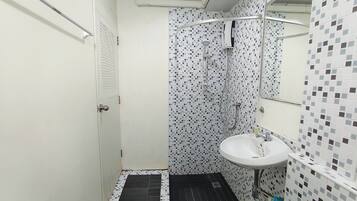 A small bathroom with a shower, a sink, and a door.