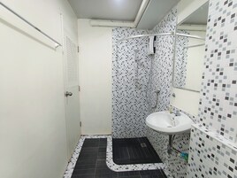 A small bathroom with a shower, a sink, and a door.