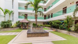 A multi-level atrium with a central garden area, palm trees, and a thatched-roof gazebo. - Laguna Bay 1  by PSR ASIA (Pattaya)