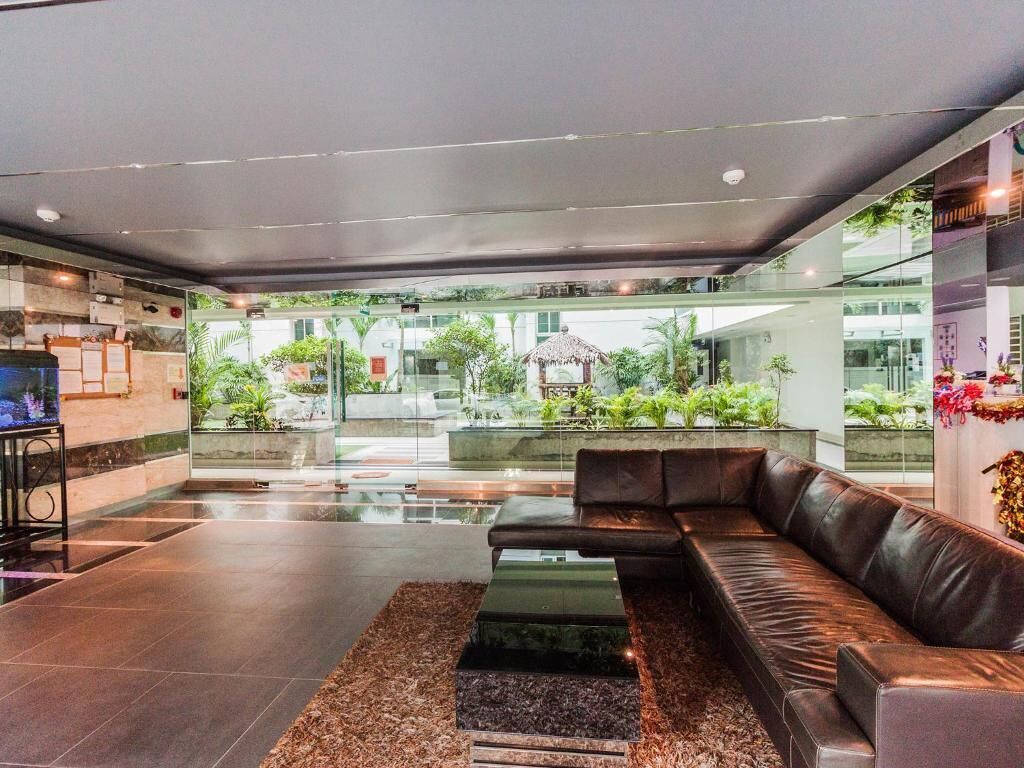 Una hall moderna con un divano in pelle, una parete di vetro e vista sul giardino esterno.