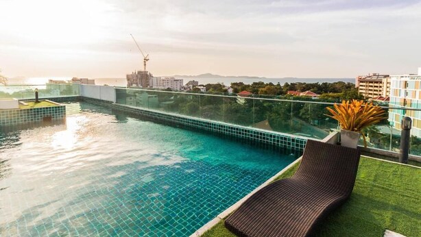 A rooftop infinity pool with a clear view of the city skyline and a construction crane in the distance. - Laguna Bay 1  by PSR ASIA (Pattaya)