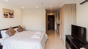 A hotel room with a bed, a television, and a bathroom visible in the background. - Laguna Bay 1  by PSR ASIA (Pattaya)