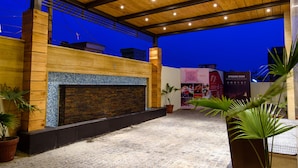 Un área de patio al aire libre con suelo de baldosas, techo de madera y chimenea de ladrillo.