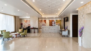 Un moderno vestíbulo de hotel con mostrador de recepción, zona de estar y paneles decorativos en la pared.