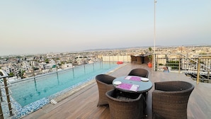 Zona de piscina en la azotea con mobiliario de mimbre y vistas a la ciudad.