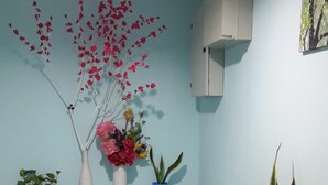 Una habitación con pared azul, un banco de madera y diversas plantas en macetas.