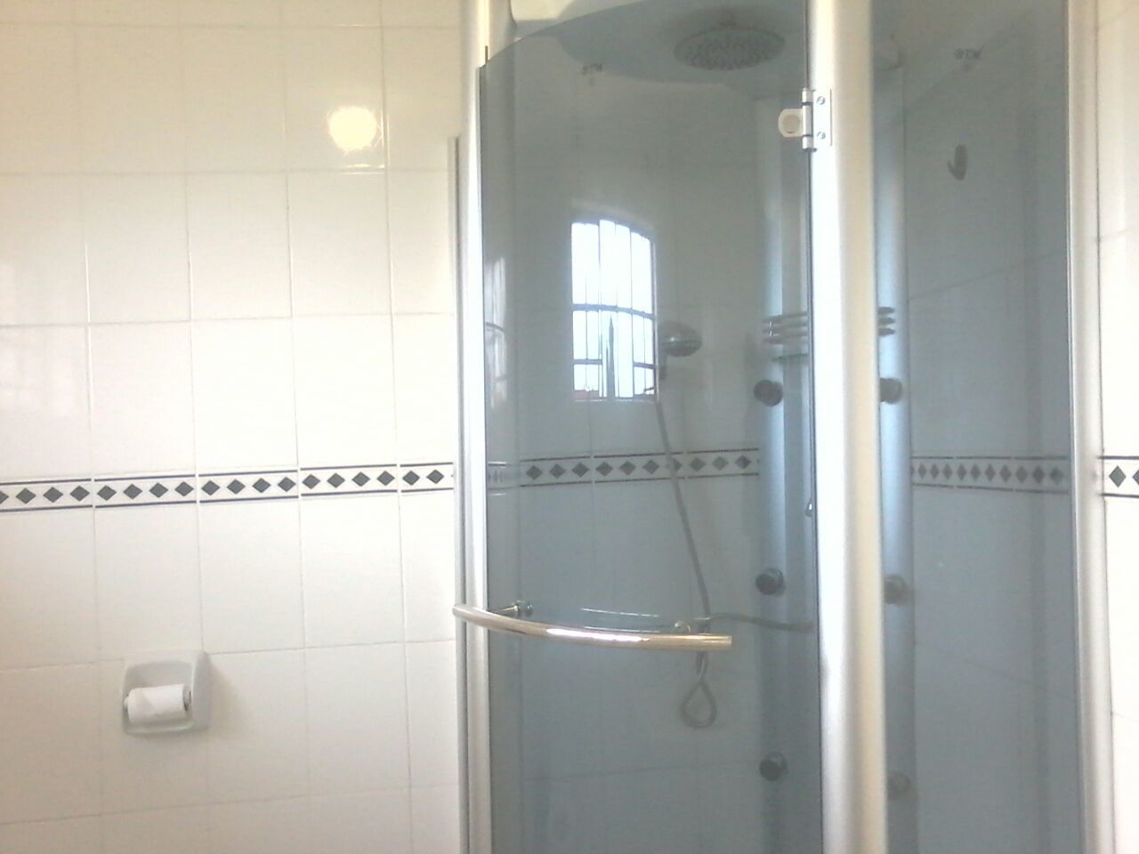 Een douche met glazen wanden, een handdouche, een glazen deur en een handdoekhouder.