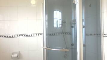 Een douche met glazen wanden, een handdouche, een glazen deur en een handdoekhouder.