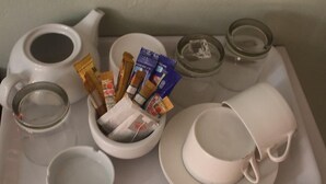 Una bandeja con tetera, tazas, un bol con aperitivos y una copa.