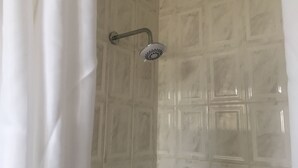 Ducha con cabezal de ducha manual y pared de azulejos.