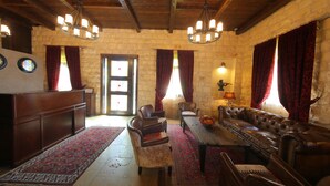 A traditional room with a stone wall, a wooden ceiling, a leather sofa, a wooden table, and a red patterned rug. - Siena Hotel (Ghazir)