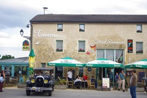 Un bar avec une terrasse et une voiture ancienne garée devant.