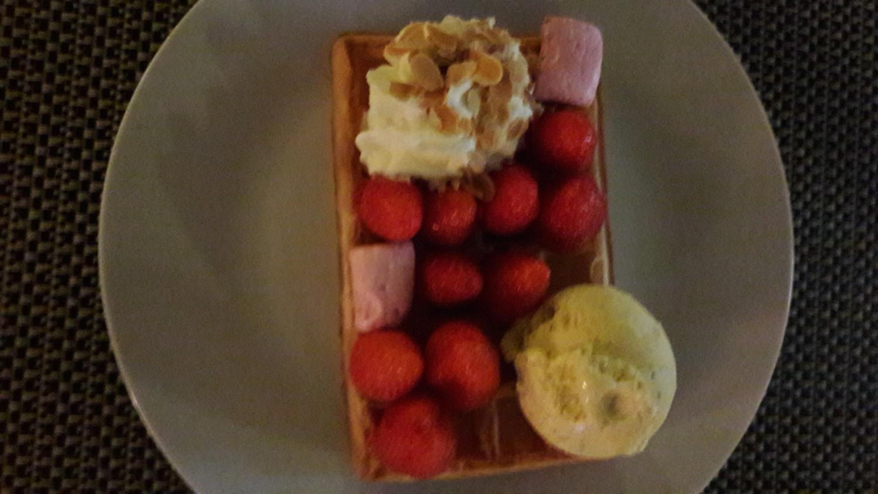 A plate with a waffle, strawberries, and a scoop of ice cream.